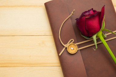 deri defter kapağı ahşap arka plan üzerinde kırmızı gül koymak