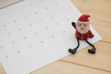 küçük Noel Baba oturumunu takvim üzerinde ahşap arka plan var