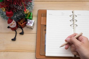 defter ve Noel Dekorasyon üzerinde yazma kalem tutan el