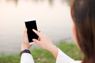 genç kadın kullanarak olmak halka açık bahçe günbatımı zaman içinde smartphone