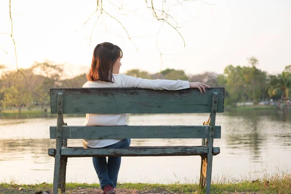 Sola mujer joven sentada en el banco y buscando en algún lugar i —  Fotos de Stock