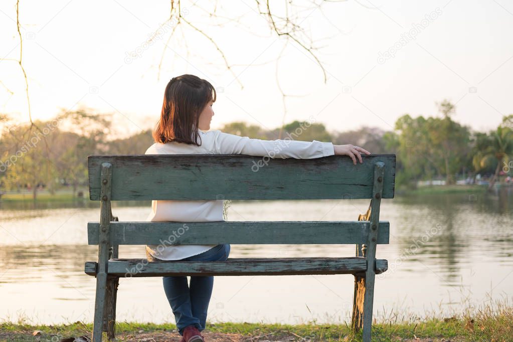 alone young woman sitting on bench and being looking somewhere i