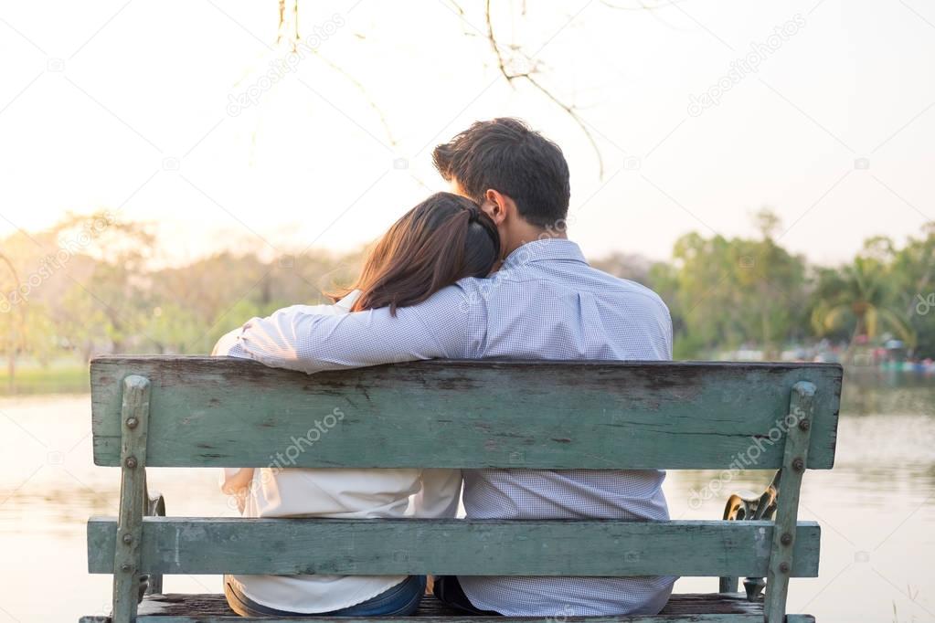 girlfriend and boyfriend sitting on bench and being hugging in p