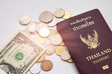 Tayland pasaportu koyarak çeşitli boyutları yığın sikke ve beyaz arka plan, bu görüntü için para tasarrufu ve seyahat kavramı ile yanındaki bir dolar nakit var.