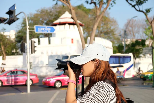 Vista laterale. Le fotografe stanno facendo dei servizi fotografici. all'incrocio e hanno uno sfondo architettonico di riferimento. questa immagine per il concetto di viaggio, ritratto e architettura — Foto Stock