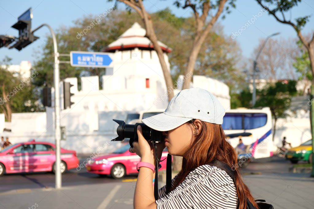 side view. female photographers are taking photo shoot something. at crossroad and have landmark architecture background. this image for travel,portrait and architecture concept