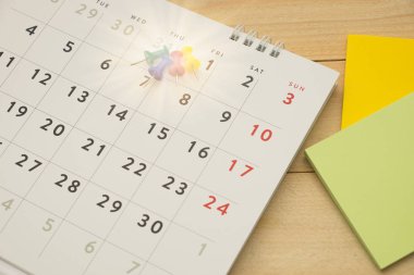 Üstten Görünüm. Masaüstü takvim koyarak pin ve yanlarında giy not var. ahşap arka plan vardır. Bu görüntü için iş Aksesuar kavramı