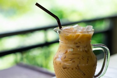 masanın üzerine koyarak cam sürahi buzlu kahve. Doğa arka plan bulanık. Bu görüntü için yiyecek ve içecek konsepti