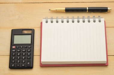 Üstten Görünüm. boş defter kağıt yanında giy ve tükenmez kalem dökeyim var siyah hesap makinesi var tüm bu ahşap koyarak arka plan vardır. Bu resim iş ve eğitim konsepti için