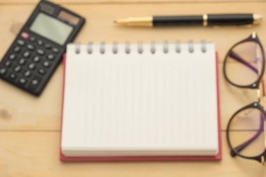 Üstten Görünüm bulanıklık odak. gözlük, defter, siyah hesap makinesi ve siyah tükenmez kalem bu ahşap koyarak tüm arka plan vardır. Bu görüntü kavramı, eğitim, iş ve donanımları için