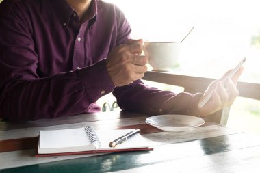 iş adamı kırmızı gömlek cep telefonuyla donatmak. sabah zamanında içme kahve fincanı tutarken. Bu görüntü için iş kavramı