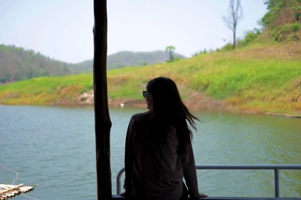 Mujer solitaria sentada en balsa de madera frente a sí misma son agua azul y otros paisajes. esta imagen para viajes, naturaleza y retrato —  Fotos de Stock