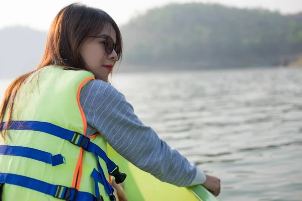 Mujer joven equipar chaleco salvavidas sentado relajante en la proa. ella mirando a su alrededor tiene mar y puesta de sol background.this imagen para la naturaleza, viajes y retrato — Foto de Stock