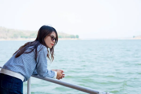 Vista lateral. joven mujer de pie sola viendo paisajes en barco. frente a ella tienen lago y montaña son de fondo. esta imagen para viajes, naturaleza y retrato — Foto de Stock