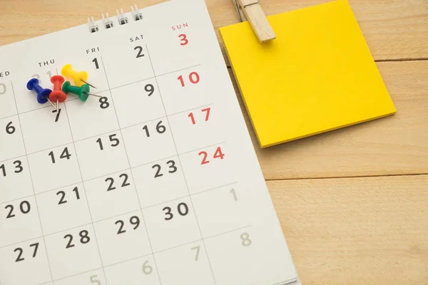 Top view. pin putting on desktop calendar and have post-it note put on beside them. wooden are background. this image for business accessory concept — Stock Photo, Image