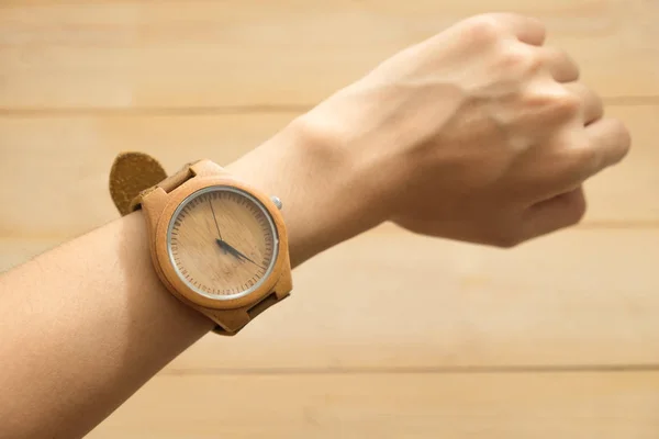 Widok z góry. Młoda kobieta wyposażyć drewniany zegarek na rękę mieć drewniane są tła. Ten obraz dla koncepcji sprzętu, akcesoriów i odzieży — Zdjęcie stockowe