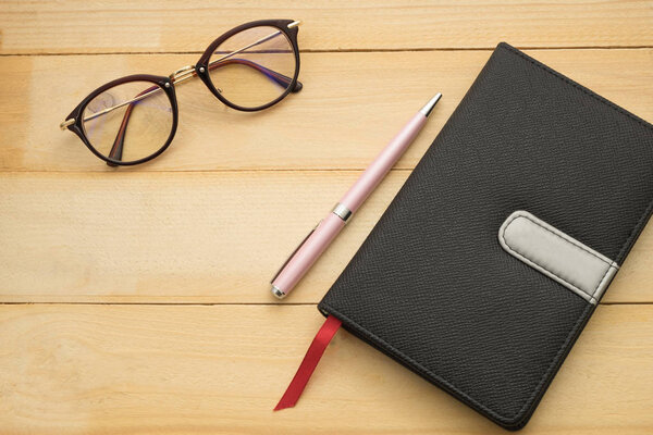 вид сверху. Стаканы, ручка и черная обложка ноутбука положить на деревянный фон. this image for education, business and equipment concept
