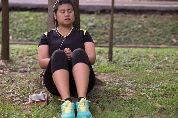 Mujer joven con auricular usando el teléfono para escuchar música y sentarse —  Fotos de Stock