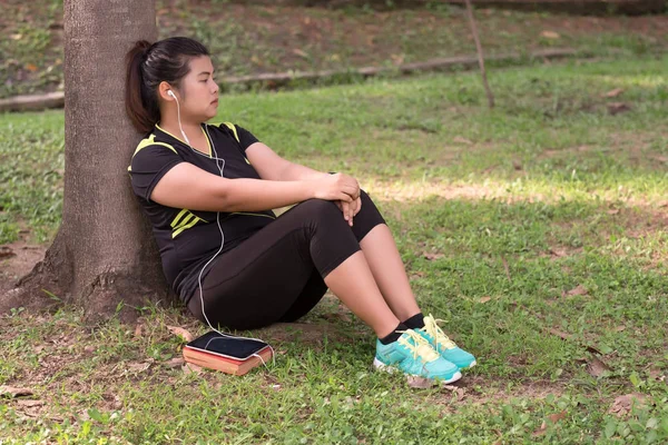 Mujer joven con auricular usando el teléfono para escuchar música y sentarse —  Fotos de Stock