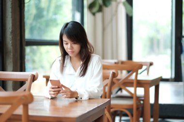 İşyerinde sabah oturan ve mobil pho kullanarak genç kadın