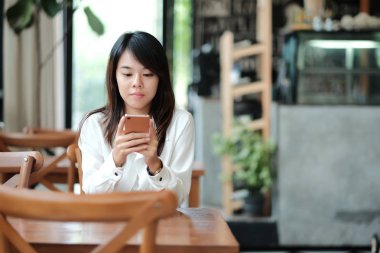 İşyerinde sabah oturan ve mobil pho kullanarak genç kadın