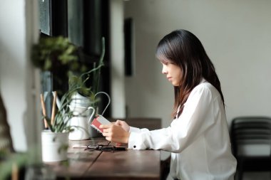 kadın tarafından Kütüphane Oda penceresinde ahşap masa kitap okur. 