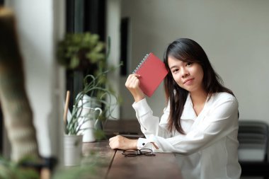 Cam kenarında oturan bir genç bayan. Ona kitap dokunmatik elinde