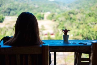tek başına genç kadın sandalyede oturmak ve dağ manzarası f bakmak