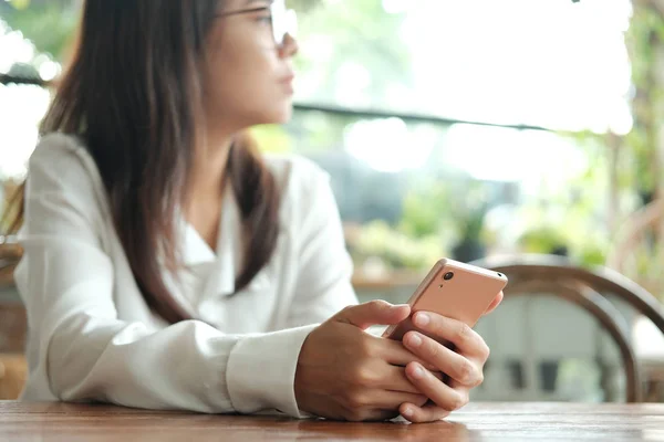 Asia mujer sosteniendo el teléfono móvil sentado y esperando a alguien — Foto de Stock