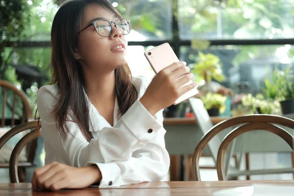 Asia mujer sosteniendo el teléfono móvil sentado y esperando a alguien — Foto de Stock