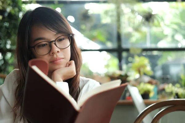 Kütüphane ve READI oturan gözlüklü genç öğrenci kadın