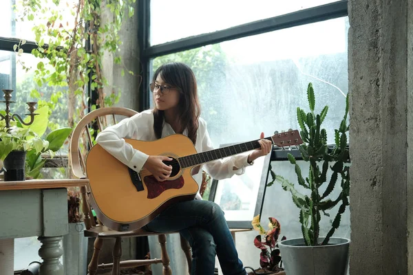 Joven mujer usando la guitarra clásica para tocar música acústica y — Foto de Stock