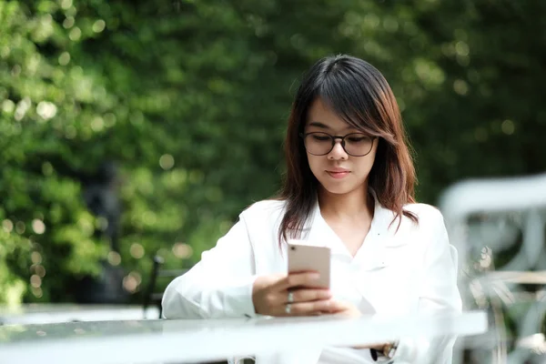 Jonge vrouw met bril zit op groene openbare tuin en h — Stockfoto