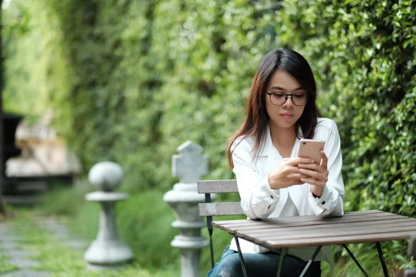 Jonge vrouw met bril zit op groene openbare tuin en h — Stockfoto