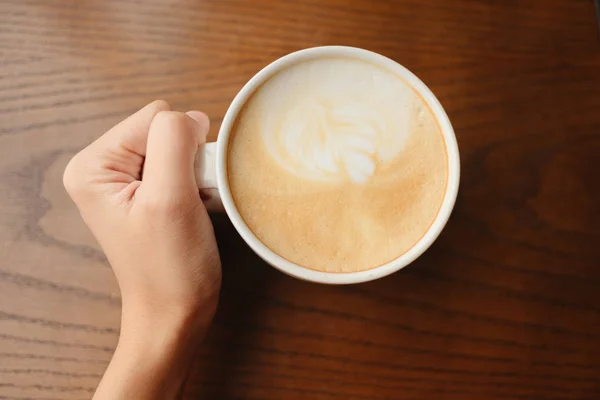 Bovenaanzicht. hand van de kop van de greep van de jonge vrouw met koffie hebben hout tabblad — Stockfoto