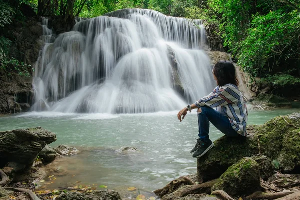 Yalnız beau ile orman arasında kayaya oturan genç kadın