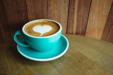 Kahve Kupası tahta masada yer üstüne bir kalp şekli vardır 