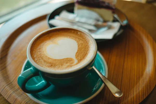 Cup met koffie heeft de vorm van een hart bovenop geplaatst op houten dienblad en — Stockfoto