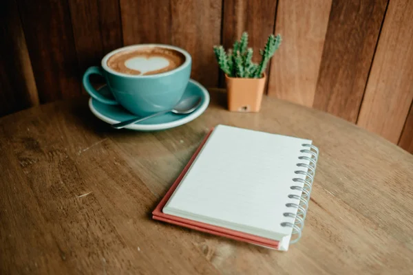 Cangkir dengan kopi memiliki bentuk jantung di atas dan plak buku catatan buku harian — Stok Foto