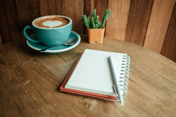 üstünde üst ve günlük defter ile bir kalp şekli ile kahve fincan vardır