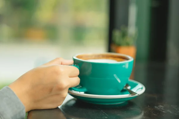 Hand van zakenvrouw houden cup met koffie geplaatst op de houten — Stockfoto