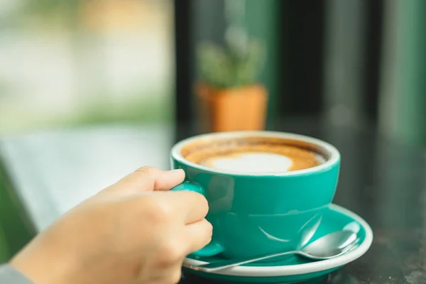 Hand van zakenvrouw houden cup met koffie geplaatst op de houten — Stockfoto