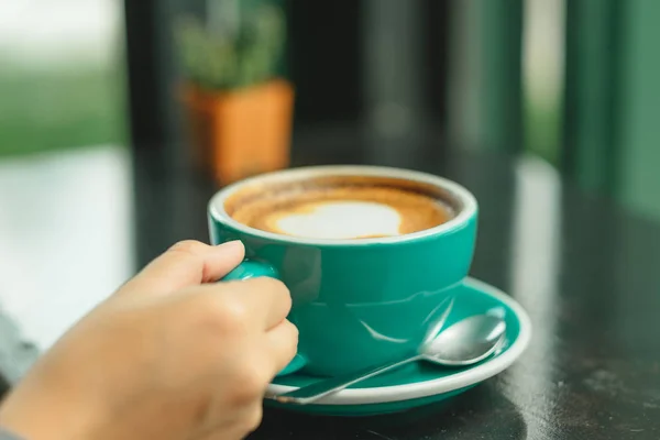 Hand van zakenvrouw houden cup met koffie geplaatst op de houten — Stockfoto