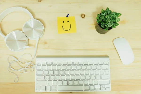 top view. headphone, post it note has smile face, keyboard, mous