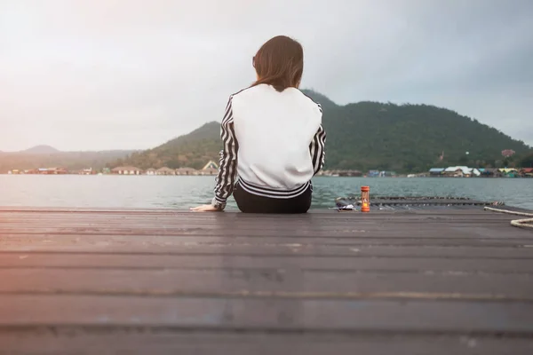 Joven mujer sentarse solo en el puente de madera tiene río, montaña, cielo —  Fotos de Stock
