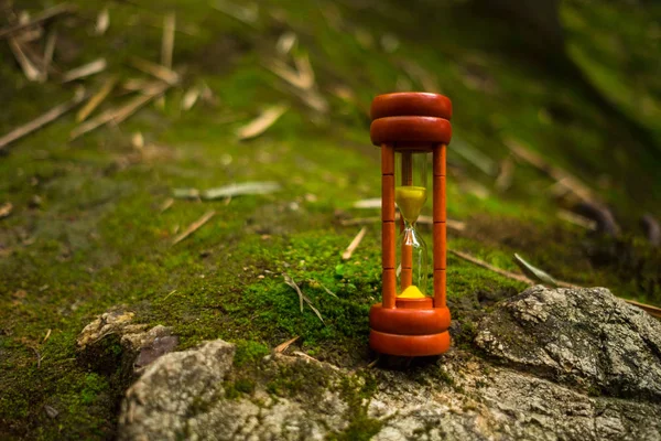 wooden sand clock with sunshine reflect placed on rock which has