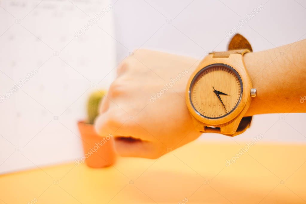 hand of businessman wearing wooden watch with calendar, plant an