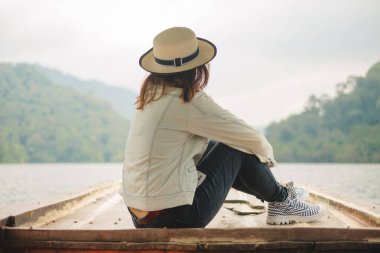 Yazın uzun kuyruklu teknenin önünde oturan Asyalı kadınlar