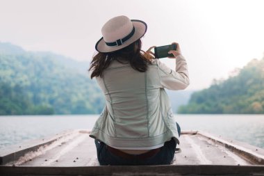 Teknenin önünde oturan Asyalı kadınlar akıllı telefondan fotoğraf çekiyorlar. 