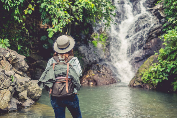 задница азиатских женщин с рюкзаком глядя водопад в лесу
 
